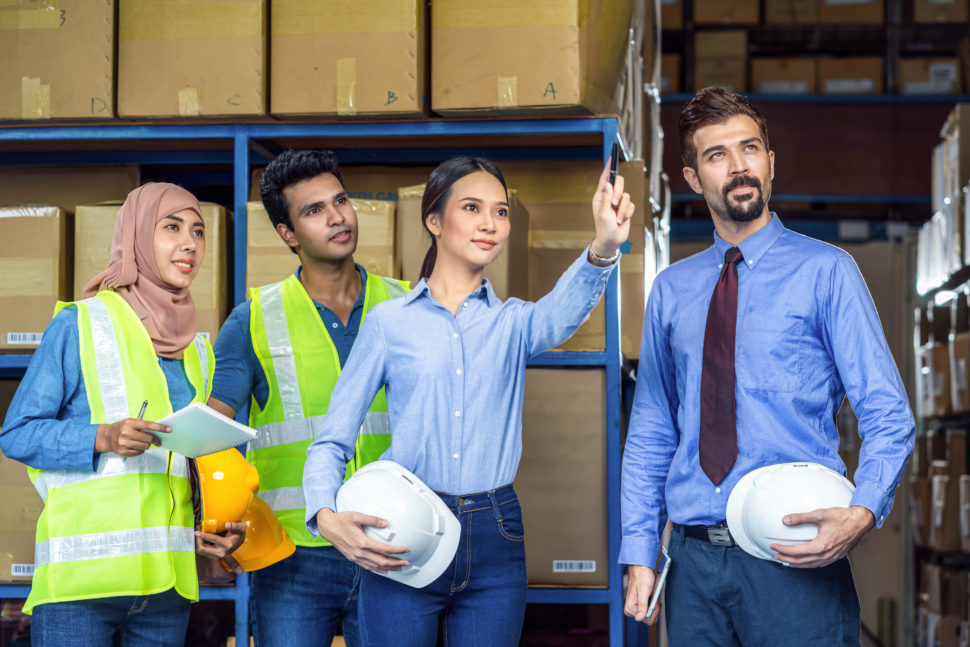woman hosts meeting with employees in warehouse