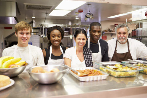 Diverse group of kitchen workers standing behind a buffet of food