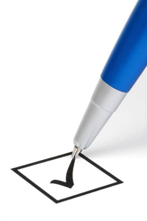 Closeup of a pen writing a check mark in a box
